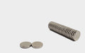 Diameter 10mm x thickness 1mm N35 neodymium round disc magnets stacked in a row and two magnets are front left of the image